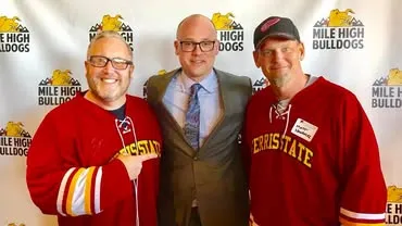Three Ferris State supporters standing in front of a Mile High Bulldogs backdrop